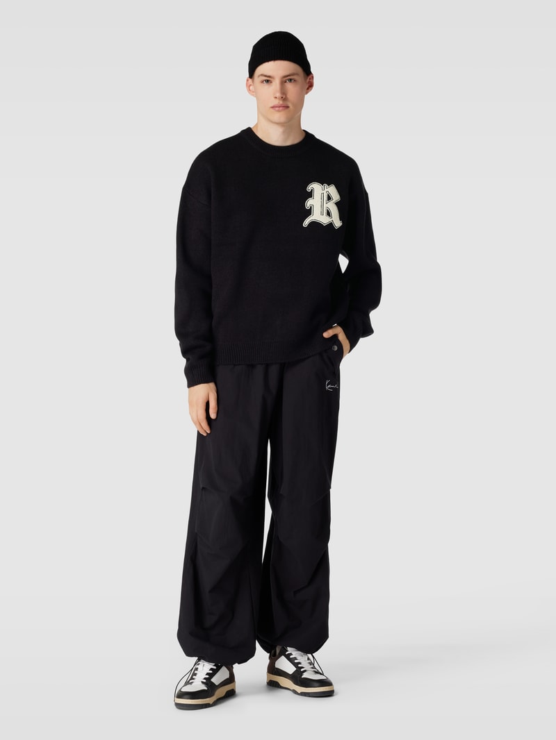 Strickpullover mit Label-Patch und überschnittenen Schultern in schwarz