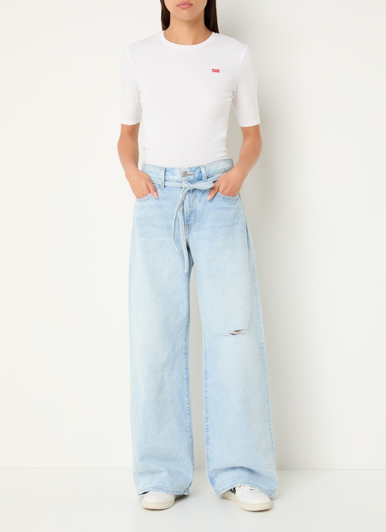 Blugi Levi's cu talie înaltă și croială largă, de culoare deschisă, cu curea legată.
