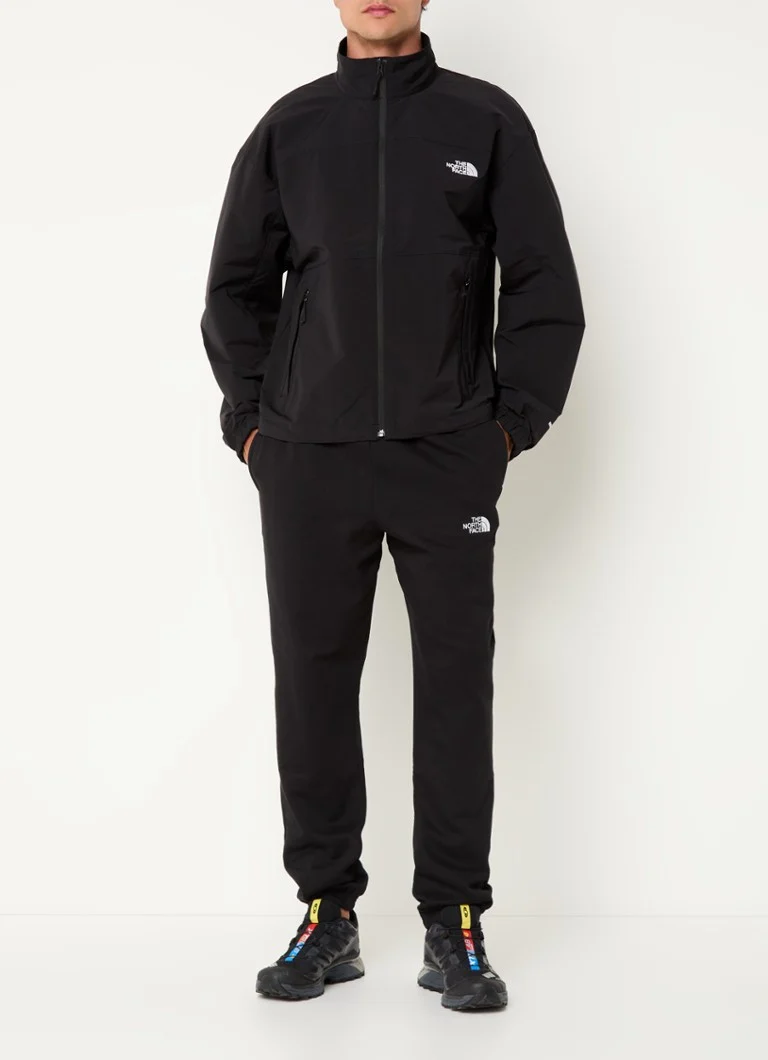 Jachetă impermeabilă cu logo-ul The North Face și buzunare cu fermoar.