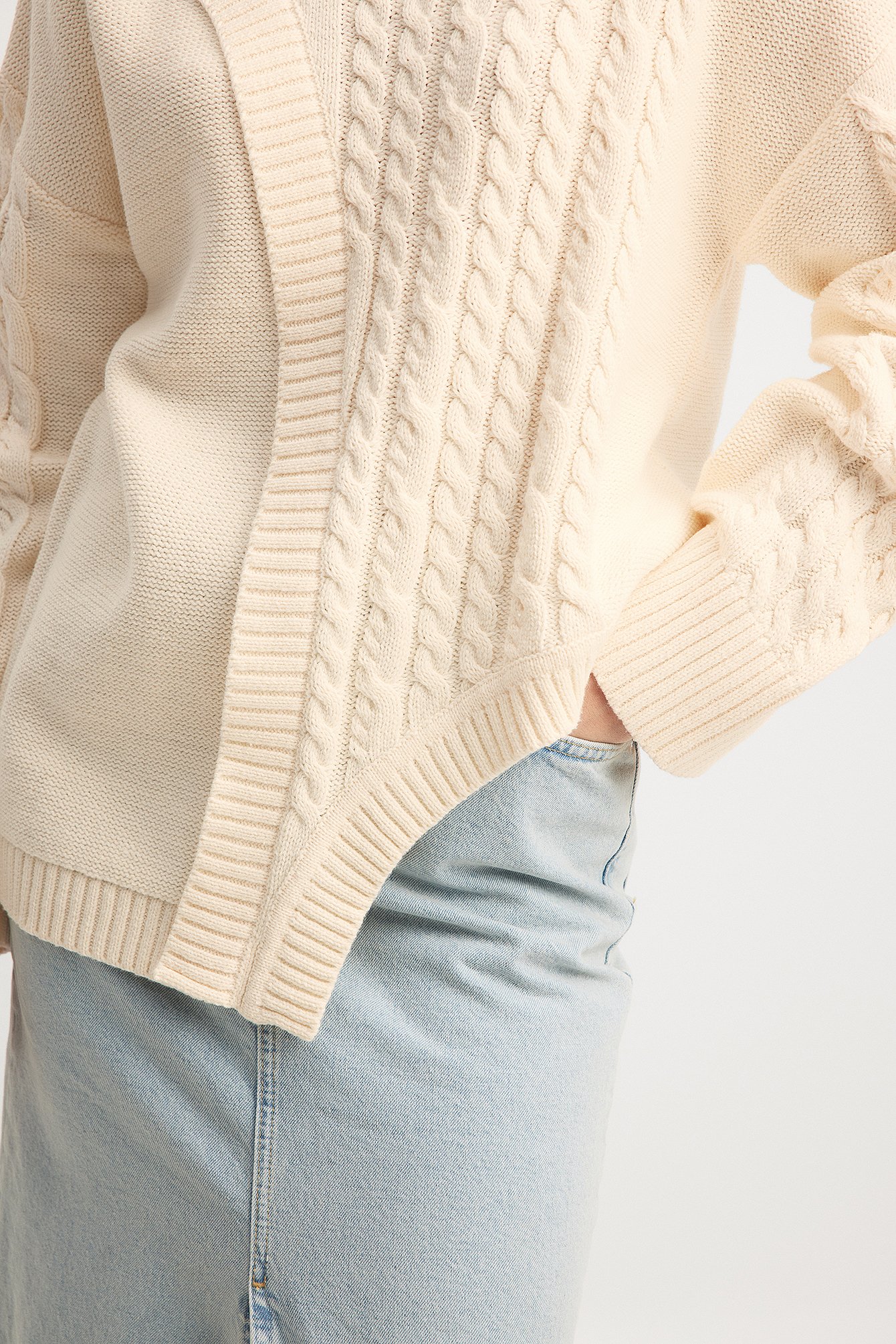 Asymmetrischer Strickpullover mit Zopfmuster