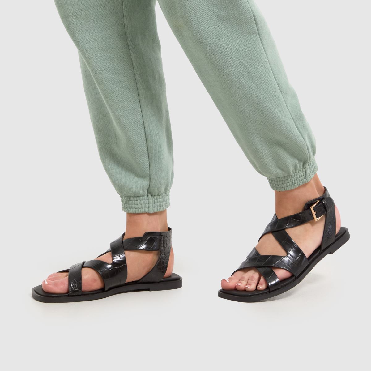 Schuh Tide – Svarta, platta sandaler med krokodilmönster
