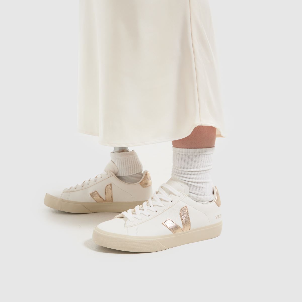 Se fältsneakers i vitt och guld.