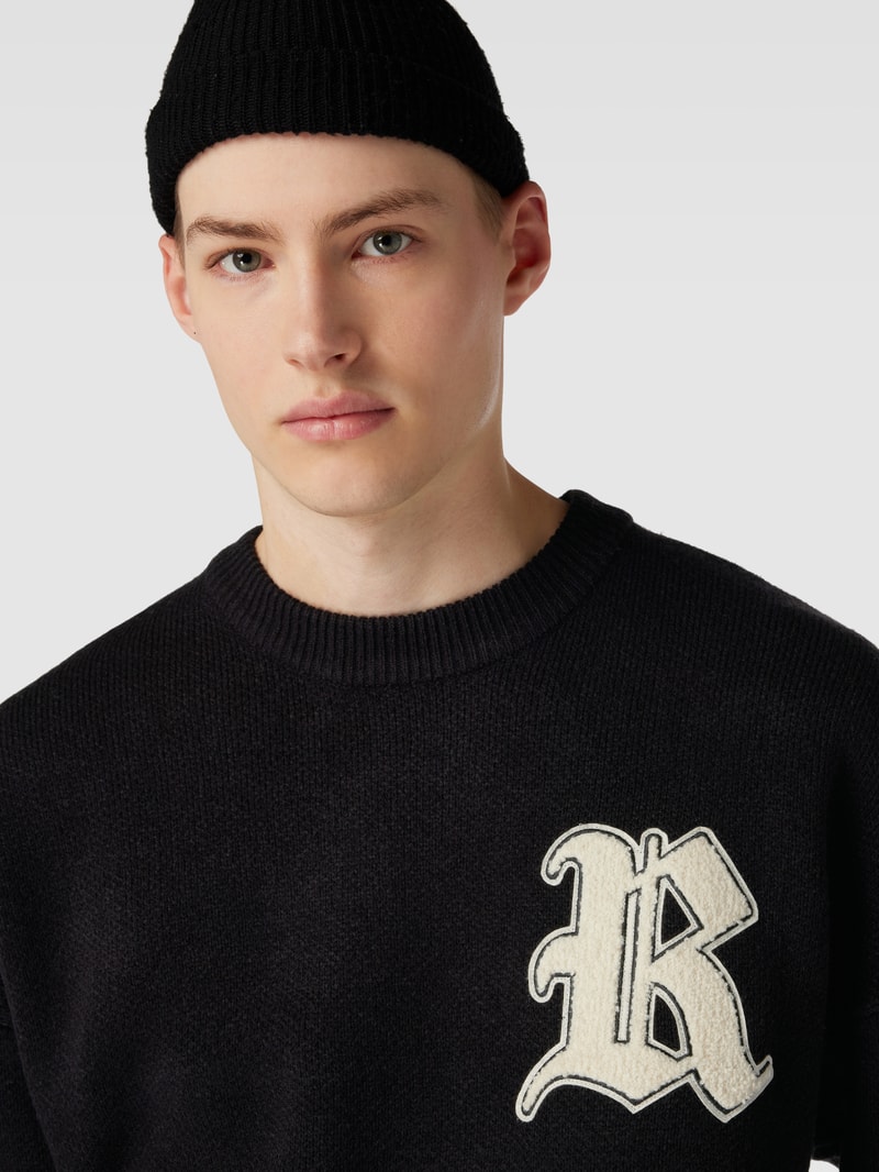 Strickpullover mit Label-Patch und überschnittenen Schultern in schwarz