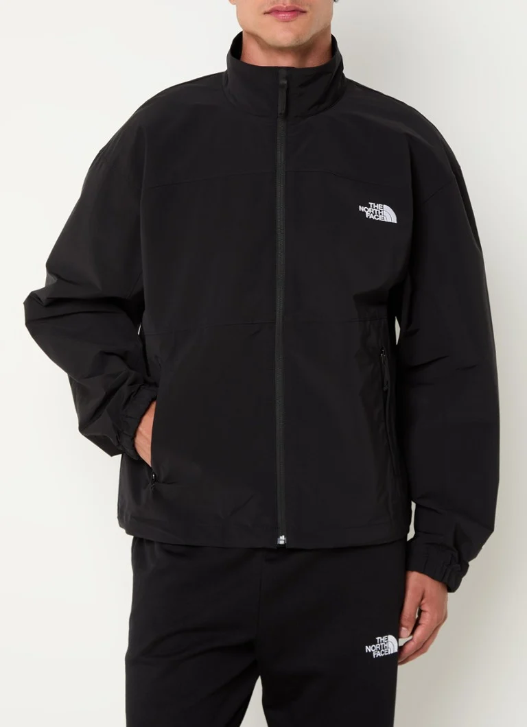 Jachetă impermeabilă cu logo-ul The North Face și buzunare cu fermoar.