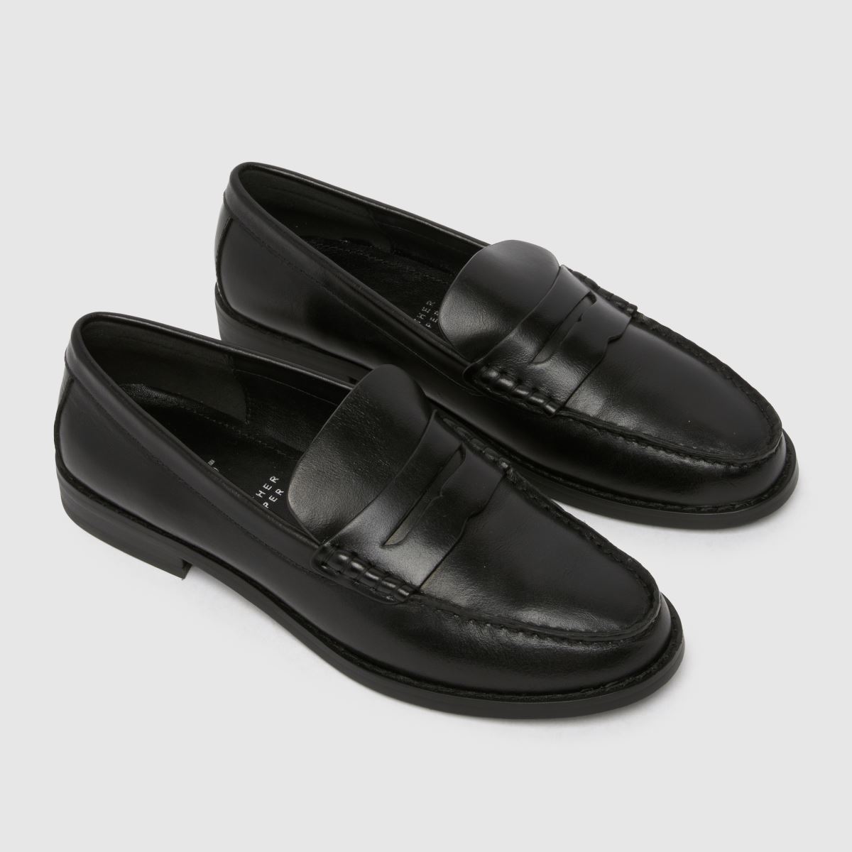 Schuh Lillian – Svarta, platta penny loafers i läder med rem