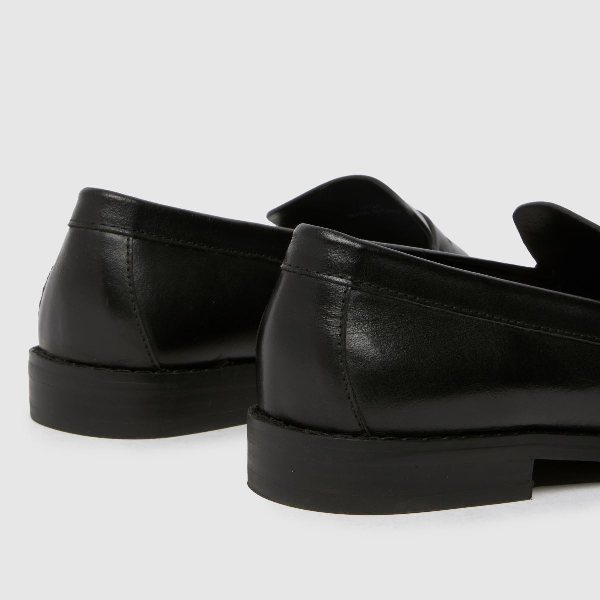 Schuh Lillian – Svarta, platta penny loafers i läder med rem